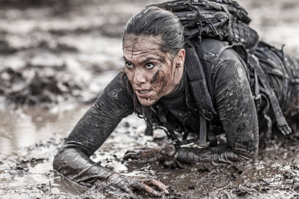Beautiful brunette female military swat security anti terror agent crawling during operations in muddy sand Beautiful brunette female military swat security anti terror agent crawling during operations in muddy sand live action role playing photos stock pictures, royalty-free photos & images