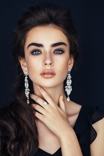 luxurious women's earrings on the delicate hand of a cute girl