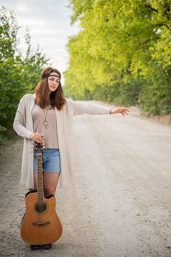pretty hippie girl with a guitar travels hitchhiking