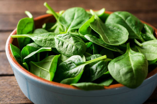 istock Fresh spinach leaves in bowl on rustic wooden table. 902666120