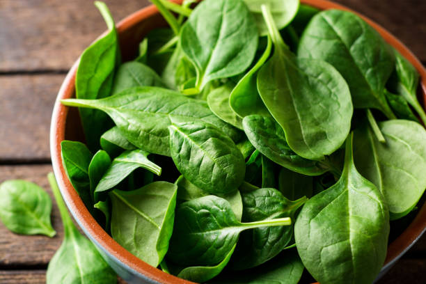 istock Fresh spinach leaves in bowl on rustic wooden table. 902666214