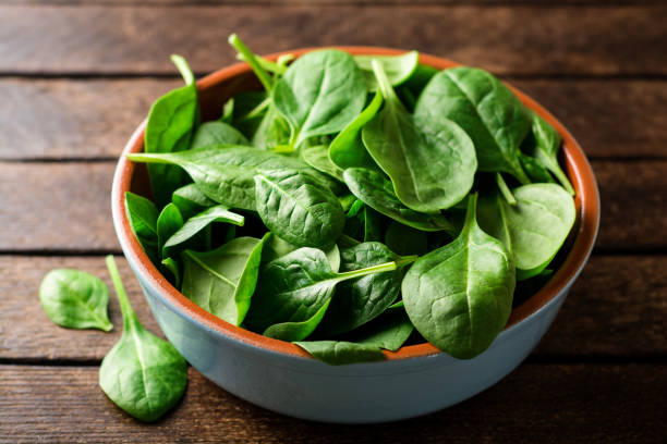 istock Fresh spinach leaves in bowl on rustic wooden table. 902666232