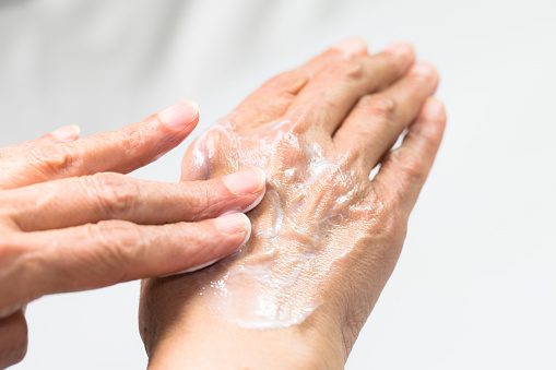 Manos de mujer Senior con francés manicura aplicando crema de manos aislada sobre fondo blanco photo