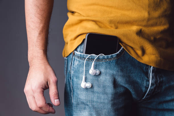 istock Mobile phone on pocket with hanging headphones 902681486