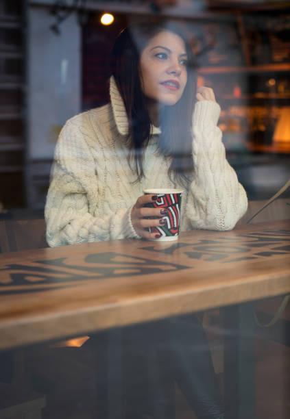 istock Young girl drinking coffee, view through the window 902696784
