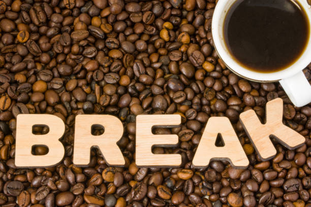 istock Coffee break photo. Cup with brewed coffee is surrounded by roasted whole grains coffee tree with word break, made of 3D wooden letters. Idea for break to drink refreshing drink in office, conferences 902706106