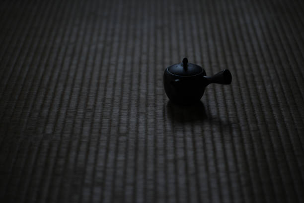 Small Japanese kyusu teapot at dusk in a dimly-lit tearoom.