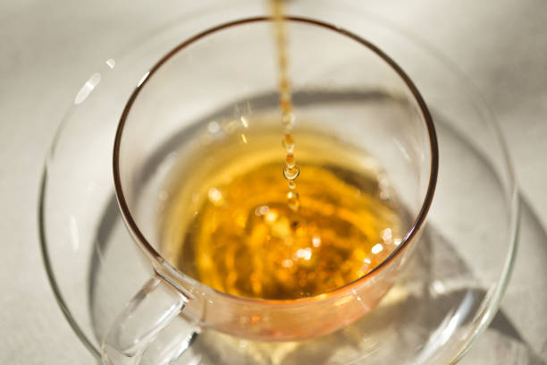 istock Black tea pouring into a glass teacup 902716296