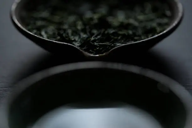 Japanese gyokuro green tea leaves in a Tokoname clay shiboridashi-style teapot on slate.
