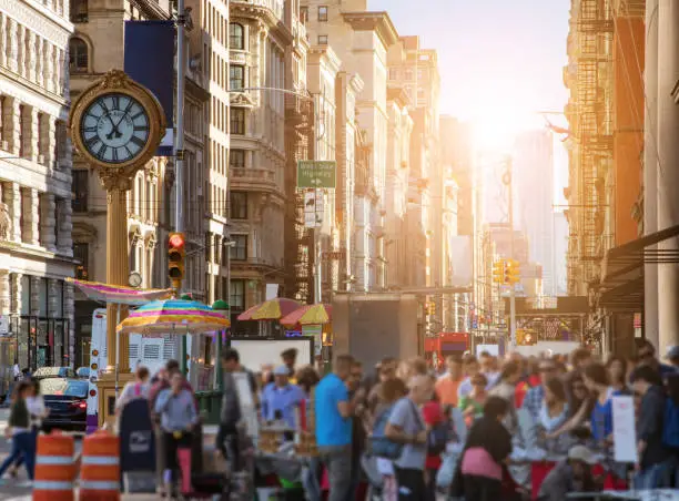 Photo of Sunlight shines on the buildings of Manhattan with crowds of people in New York City