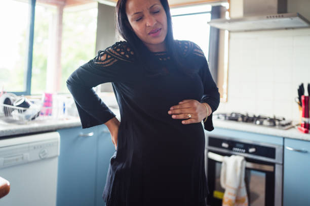 istock Woman standing in kitchen while having strong back pain. 902746596