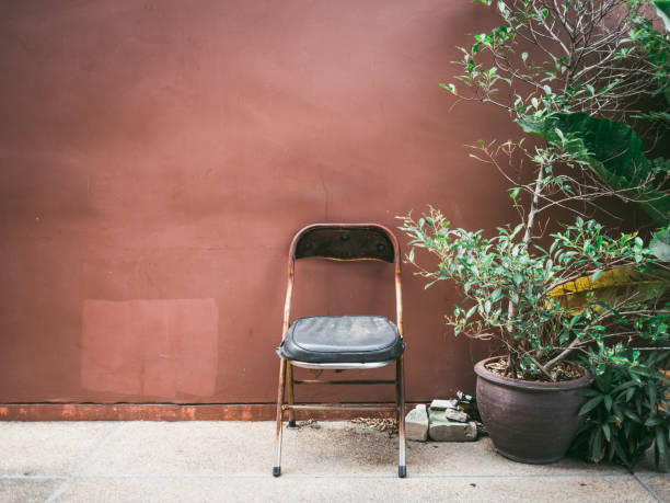 istock Old cheap rusty chair with plant by grunge brown wall. 902746966