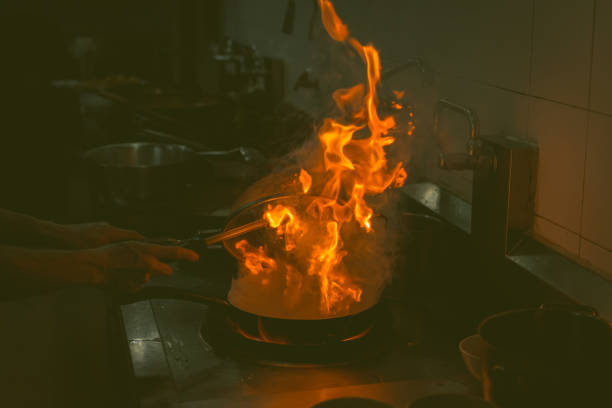 istock Chef cooking and doing flambe on food in restaurant kitchen 902750028