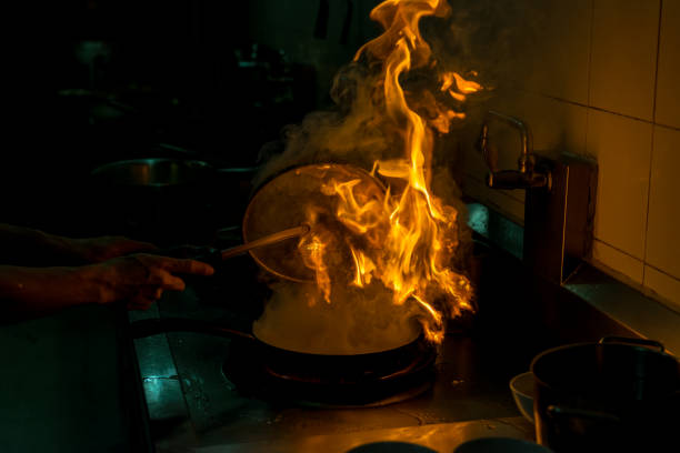 istock Chef cooking and doing flambe on food in restaurant kitchen 902750198