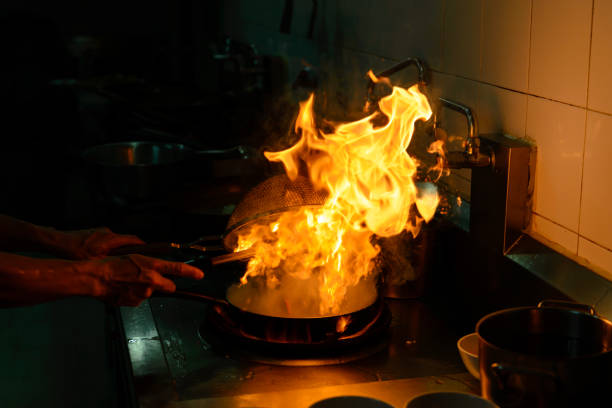 istock Chef cooking and doing flambe on food in restaurant kitchen 902750432