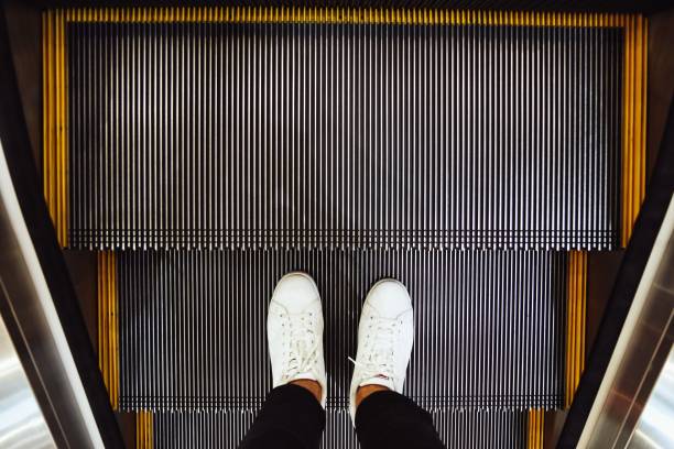 selfie of  man feet in white sneaker shoes on escalator steps in the shopping mall, top view in vintage style - business human foot shoe men imagens e fotografias de stock