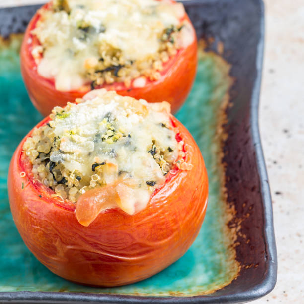 istock Baked tomatoes stuffed with quinoa and spinach topped with melted cheese on a ceramic plate, square format 902757322