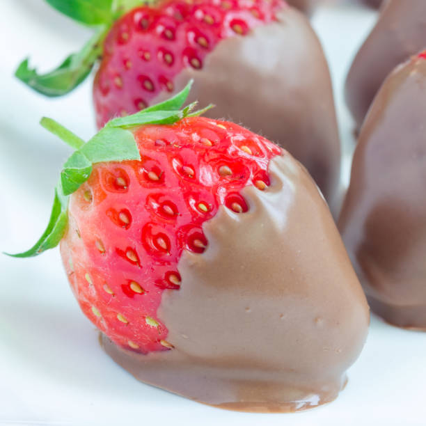 istock Strawberries covered with milk chocolate on a white plate, closeup, square 902757330
