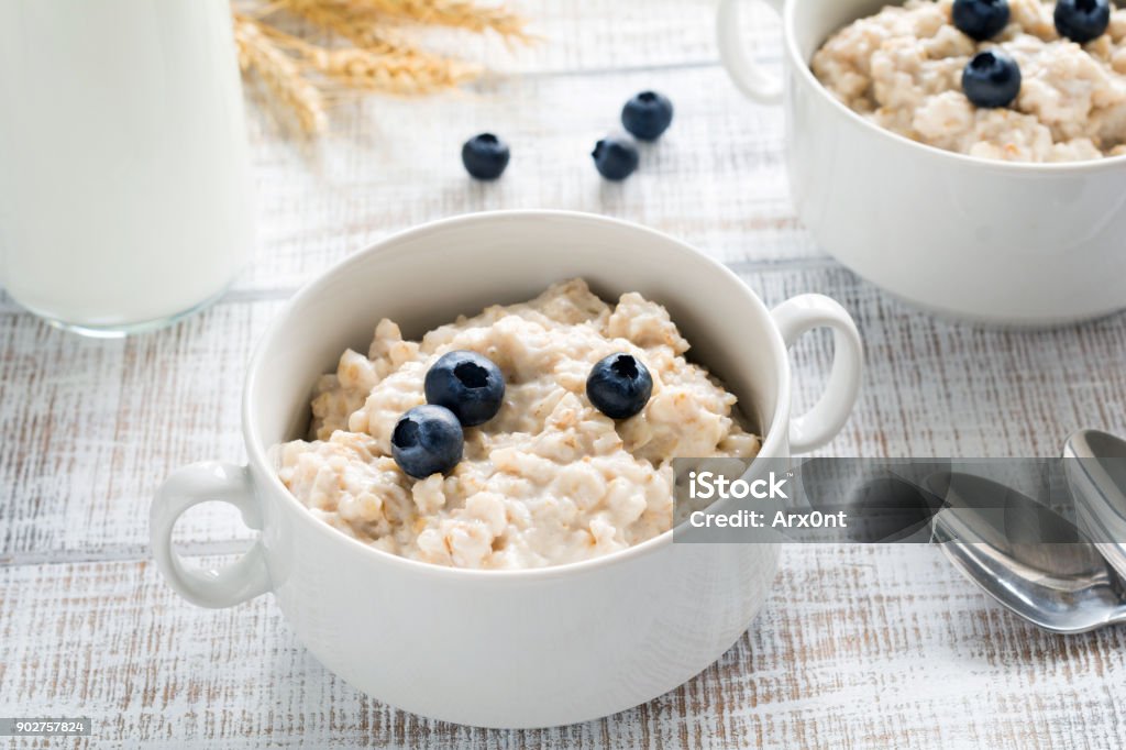 Oatmeal porridge with blueberries in white bowl Oatmeal porridge with blueberries in white bowl on old white table. Horizontal. Healthy eating, healthy lifestyle concept Blueberry Stock Photo