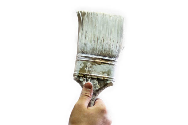 istock Hand holding an old paint brush with white paint 902767476