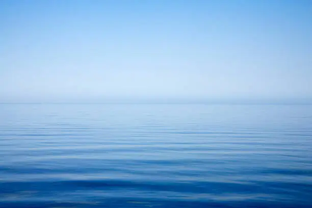 Background of sky and sea, sea is very calm with gentle ripples, sky perfectly clear.