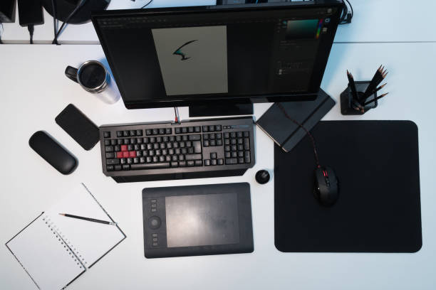 istock Designer's workplace. A white table on which stands a monitor, a mug, a notebook, pencils, a mouse, a graphic tablet and glasses 902783834