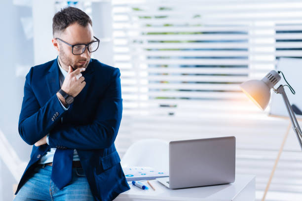 Calm smart man in glasses looking at the lamp while thinking