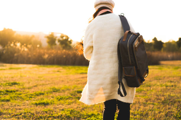istock reaw view of woman with backpack walking on grass 902791284