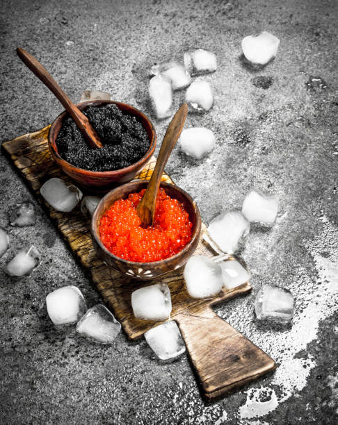 istock Black and red caviar in a bowl on the old Board. 902793932