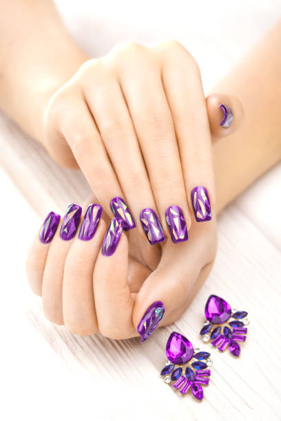 istock violet manicure with earrings on the white wooden table. 902794022