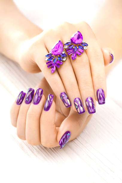 istock violet manicure with earrings on the white wooden table. 902794126