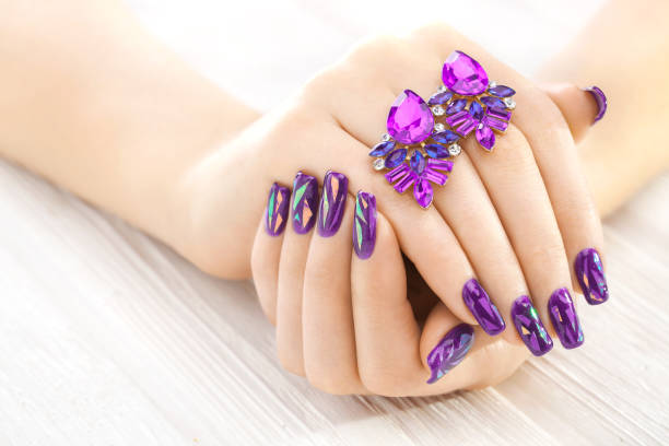 istock violet manicure with earrings on the white wooden table. 902794172