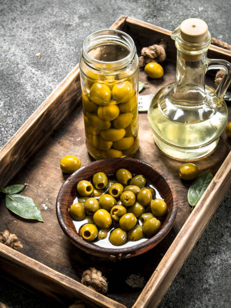 istock Olive oil with pickled olives on an old tray. 902794326