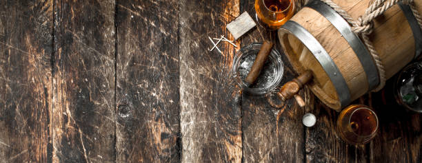 Barrel with French cognac, glasses and a cigar. On a wooden background.