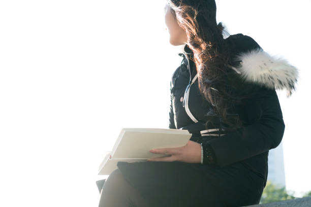 Pretty woman reading a book and covering her face isolated on white