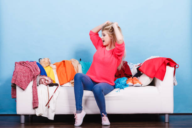 istock Woman does not know what to wear sitting on couch 902801594