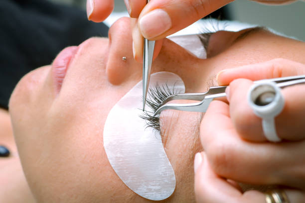 Eyelash extension procedure, woman eye with Long eyelashes stock photo