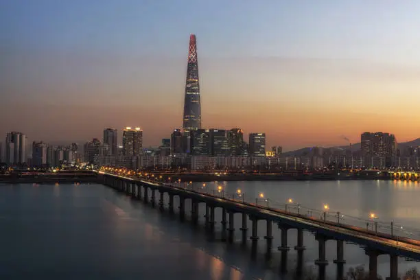 the iconic lotte tower taken at sunset with the view of jamsil railway bridge over the han river. Seoul, South Korea