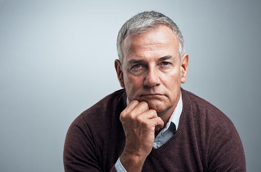 Studio shot of a mature man looking serious against a gray background