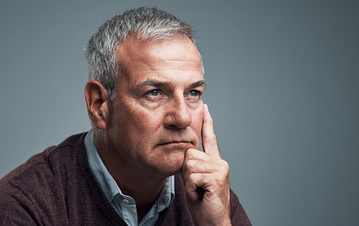 Studio shot of a mature man looking thoughtful against a gray background