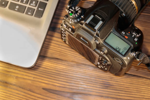 istock Laptop and photo camera on wooden background 902809078