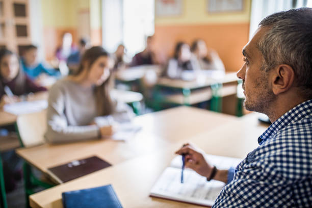 istock Profile view of mid adult high school teacher during the class. 902811384