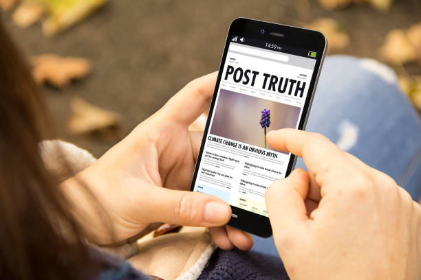 istock woman with post truth phone in the park 902819410