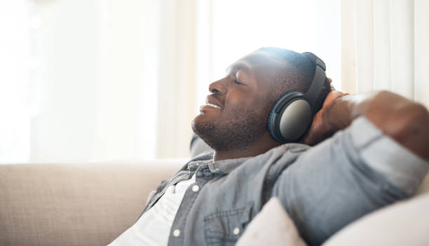 Music makes all seem good in the world Cropped shot of a handsome young man relaxing at home with his headphones on bachelor stock pictures, royalty-free photos & images