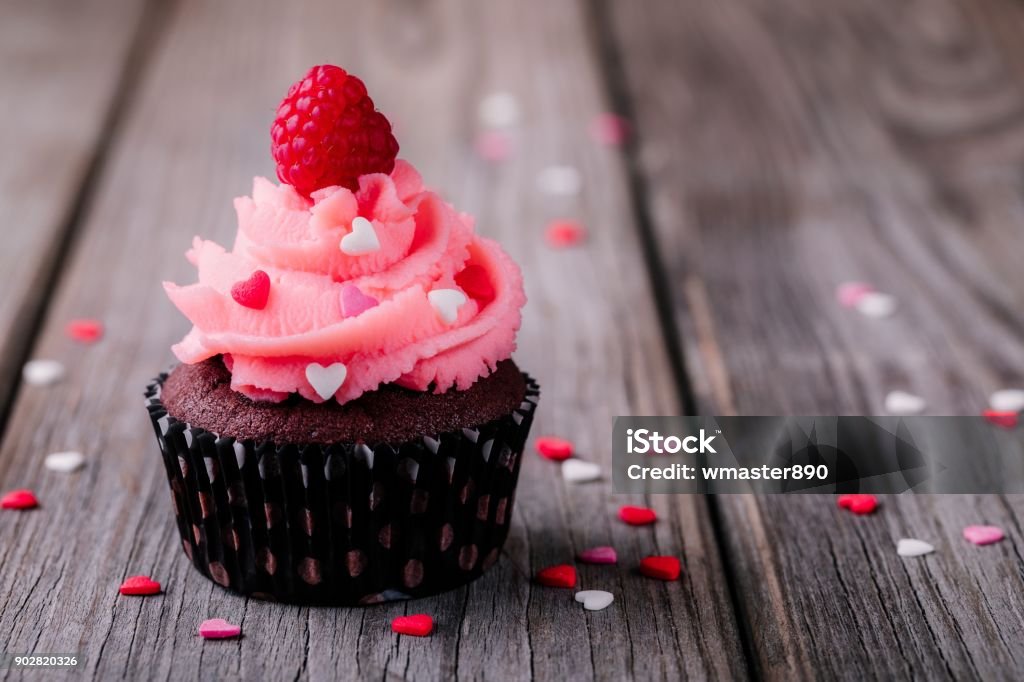 Petits gâteaux au chocolat avec crème rose, les cœurs de sucre et les framboises fraîches pour la Saint-Valentin - Photo de Cupcake libre de droits