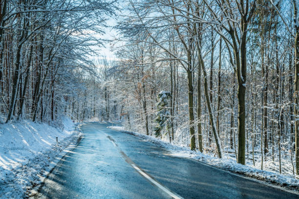 4 jahreszeiten - eisiger landstraße im wald am kalten wintertag - winterroad stock-fotos und bilder