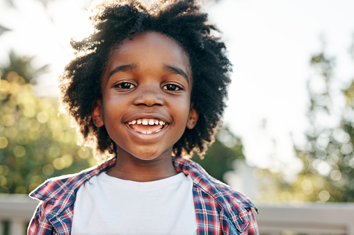 Portrait of a cheerful little boy smiling at the camera outside during the day