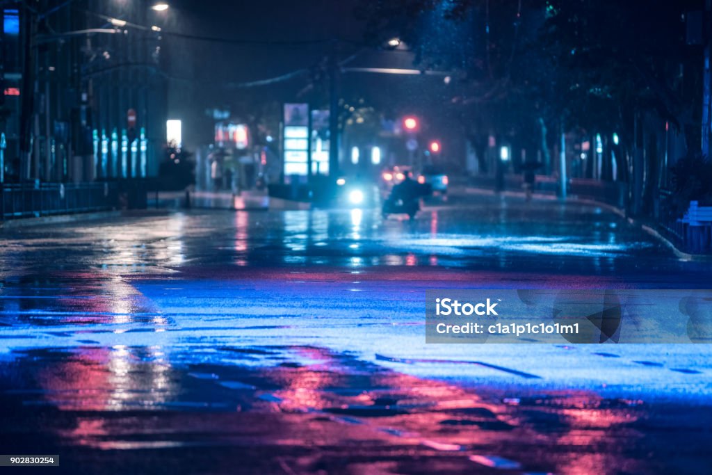 Auto che guidano su strada bagnata sotto la pioggia e luci colorate riflesse sulla strada asfaltata bagnata - Foto stock royalty-free di Notte