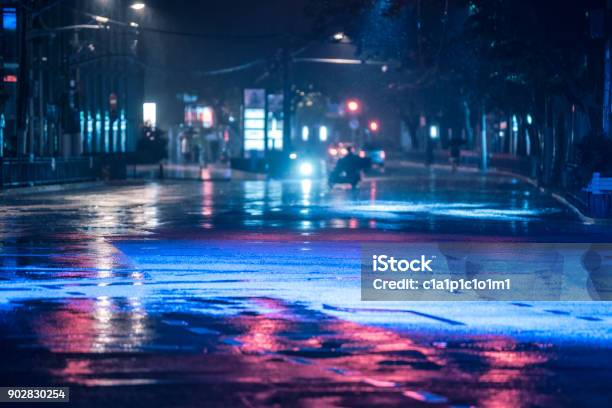 Cars Driving On Wet Road In The Rain And Colored Lights Reflected On The Wet Asphalt Road Stock Photo - Download Image Now