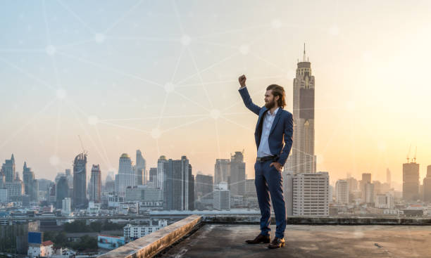 Successfull business in suit on rooftop with city scape in the background with connecting dots stock photo